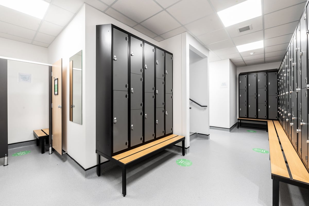 PureGym Chelmsford Meadows: Rows of metal lockers, wooden benches in a changing room setting.