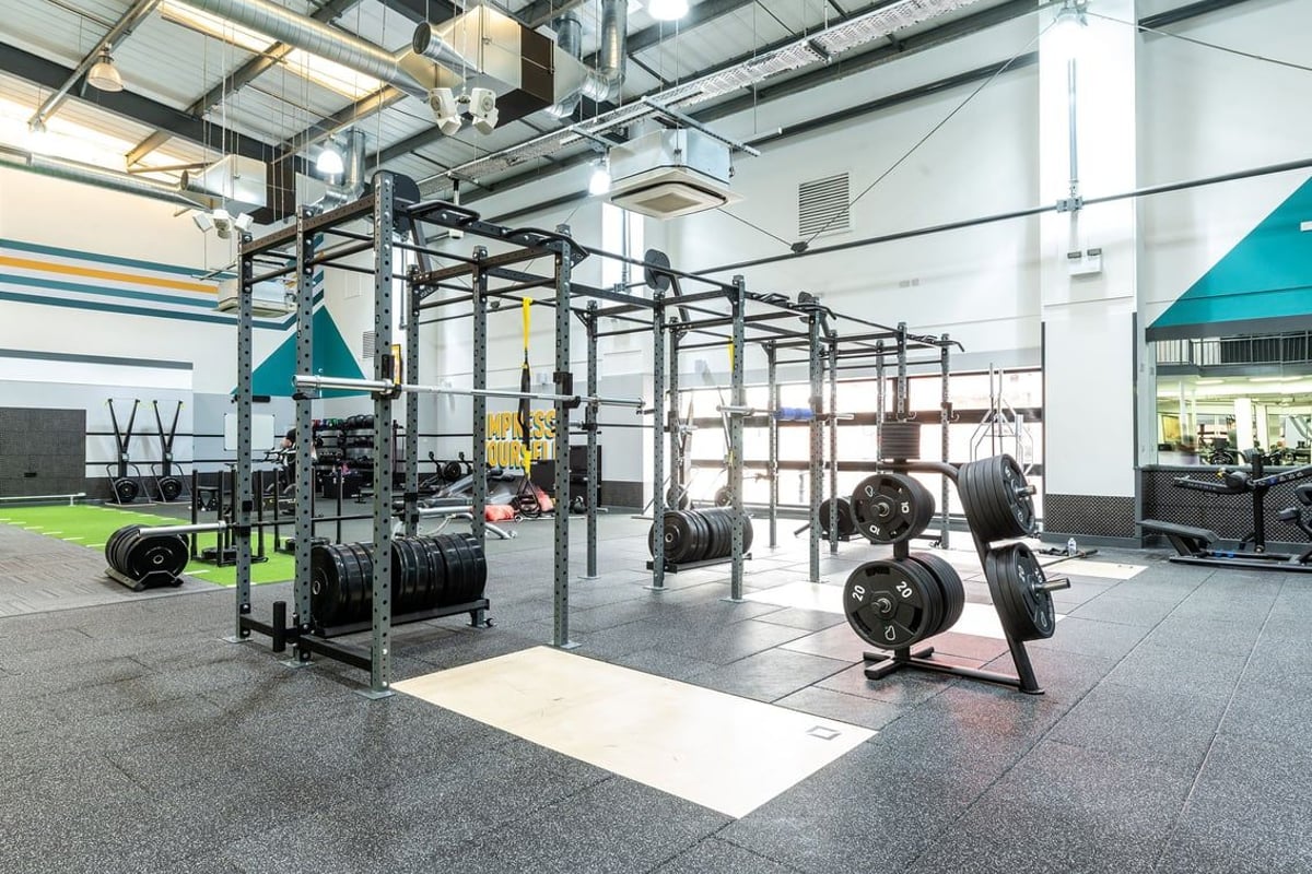 PureGym Aintree: Squat racks, weight plates, rubberized flooring in a functional training area.