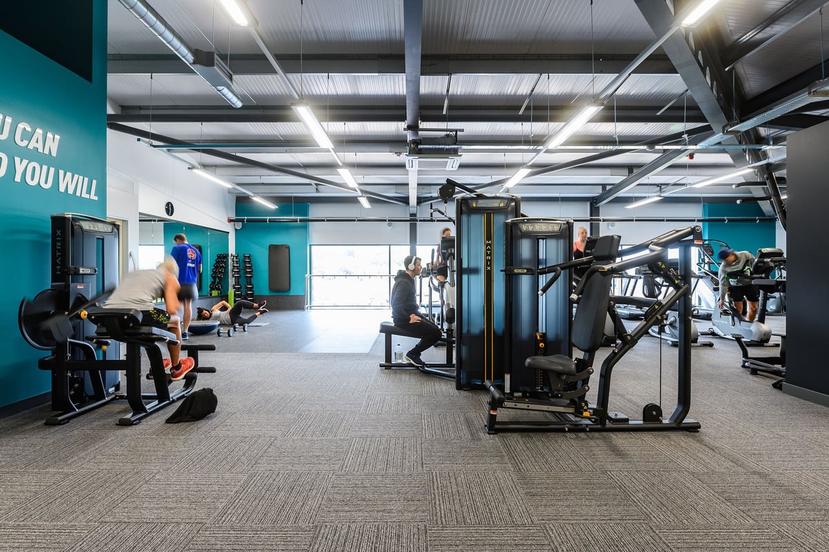 PureGym Barnstaple: Strength machines, benches, free weights, and motivational signage in a teal-accented gym space.