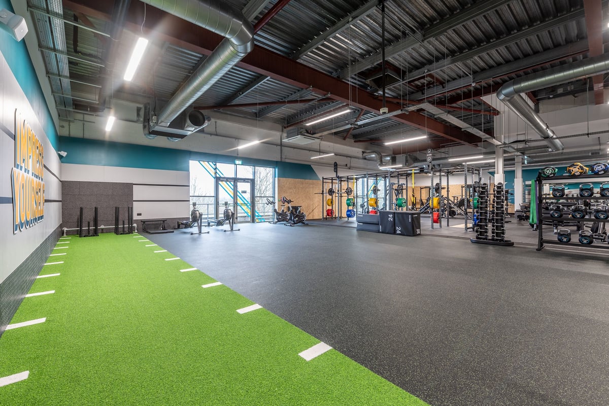PureGym Craigavon: Large fitness area with weightlifting platforms, squat racks, turf section, and dumbbell racks.