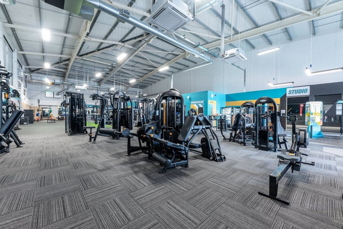 PureGym Durham City Retail Park: Gym studio with weight machines, free weights, mirrors along walls, and rubberized flooring.
