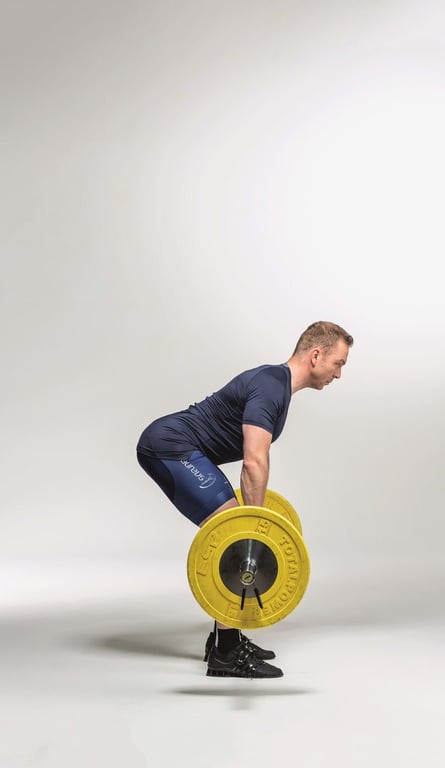 Man in sportswear lifting a barbell with yellow weights in a studio setting