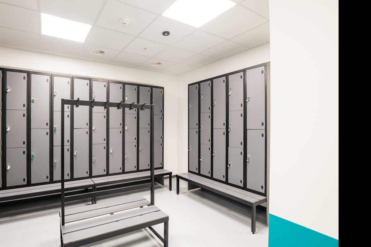 PureGym Genf Le Bouchet: Rows of lockers, benches for changing, entry gates to secure fitness area.