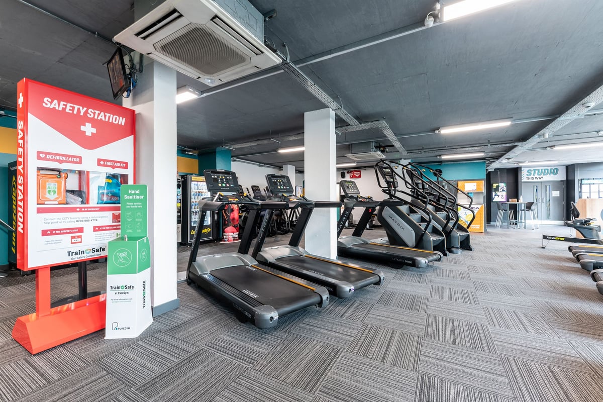 PureGym London Finsbury Park: Rows of treadmills, safety station kiosk, and air conditioning units overhead.
