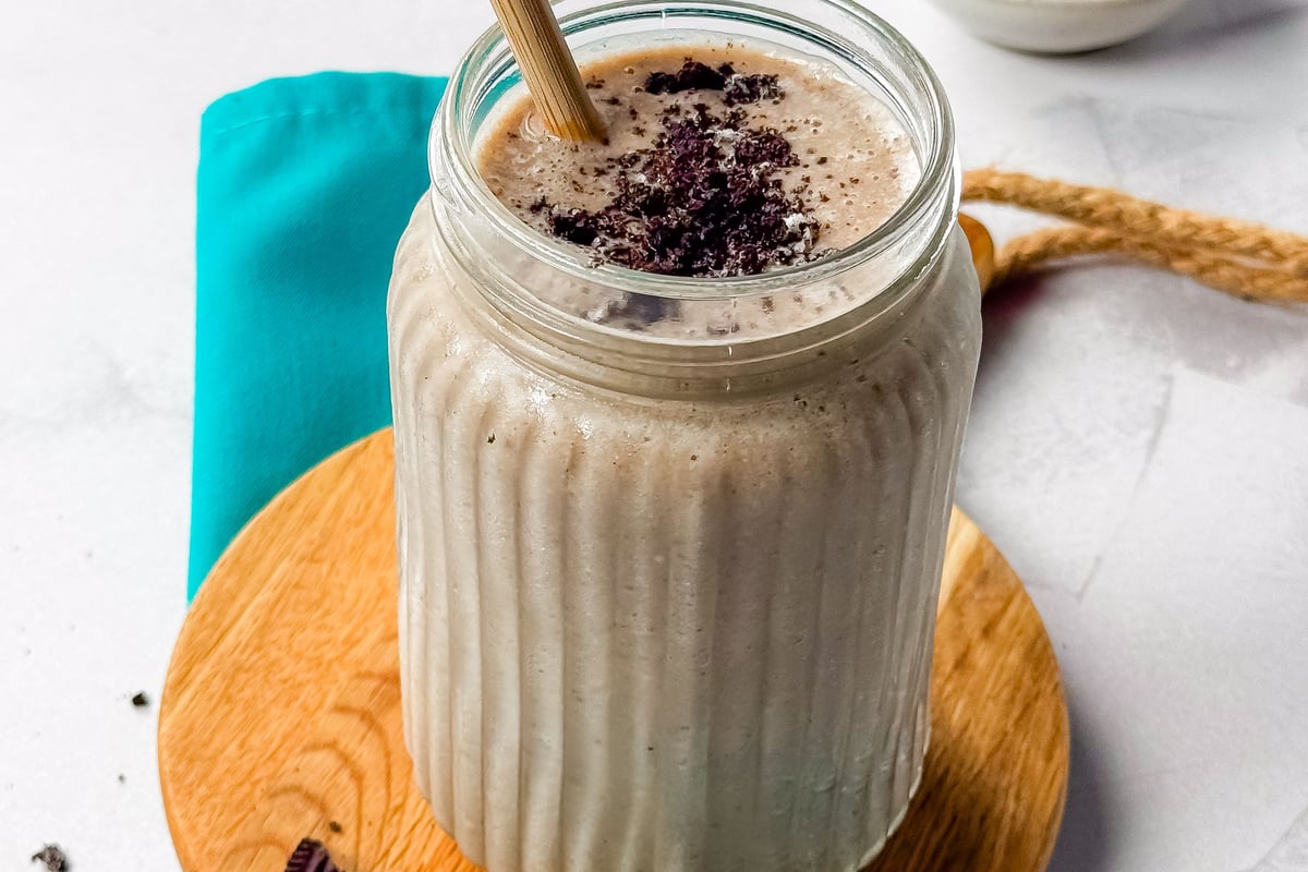 Milkshake with crushed chocolate cookies in a ribbed glass jar with a bamboo straw