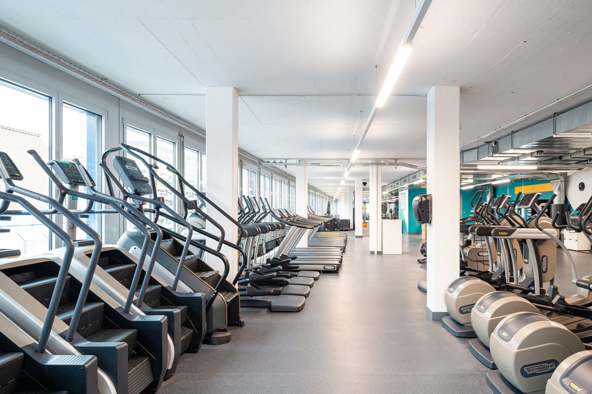 PureGym Altstetten: Reihen von Laufbändern und Heimtrainern in einem hell beleuchteten PureGym-Cardiobereich.
