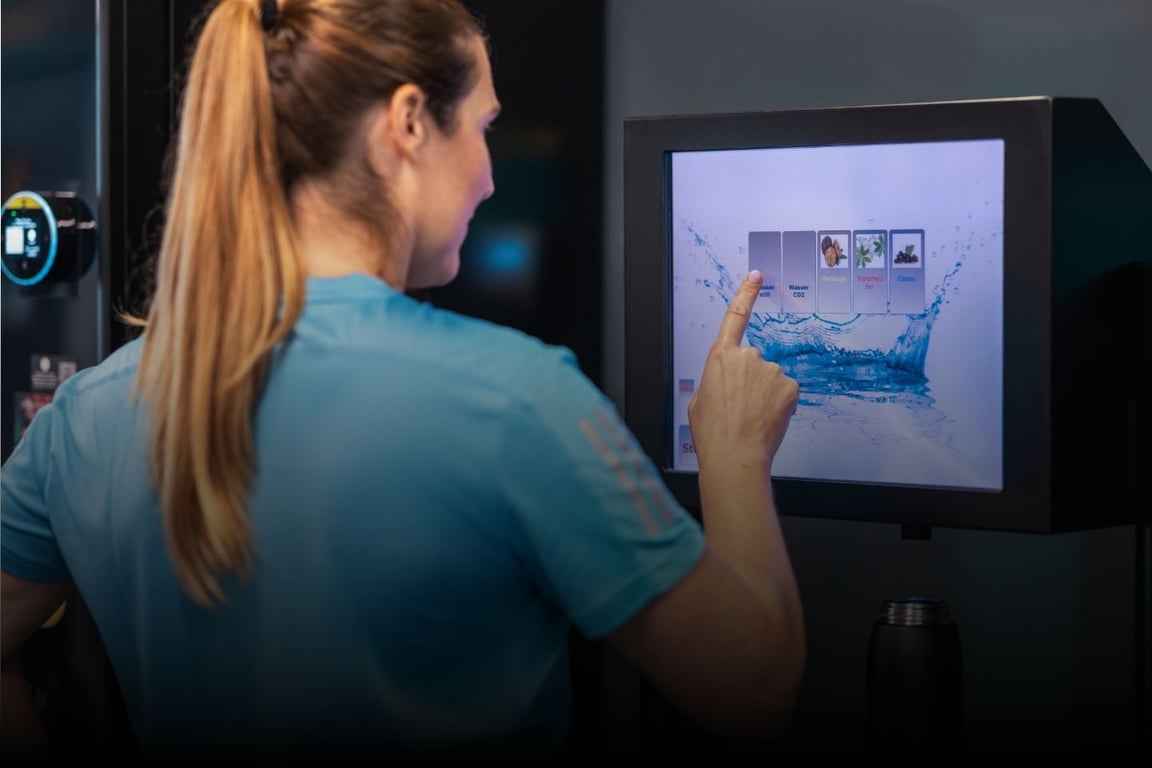 PureGym female member selecting membership add-ons on a touch screen.