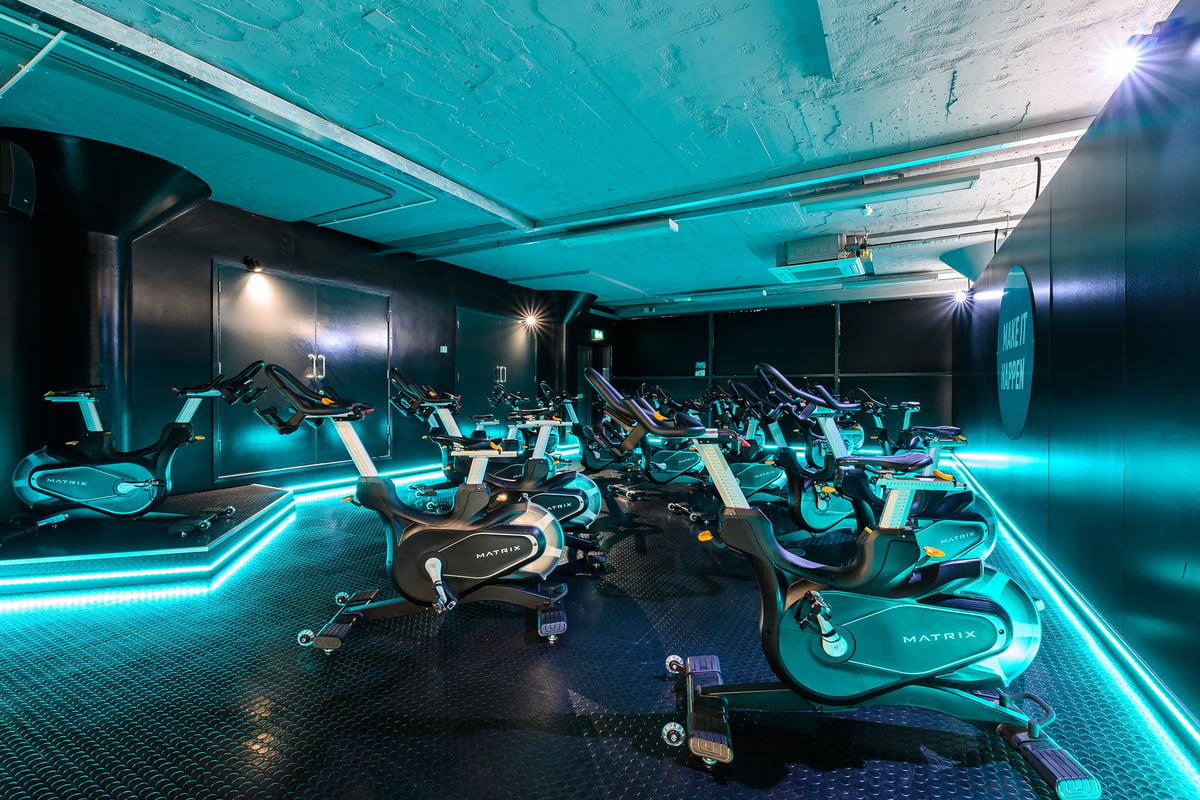 PureGym Nottingham Basford: Rows of futuristic exercise bikes with blue lighting in a dimly lit gym studio.