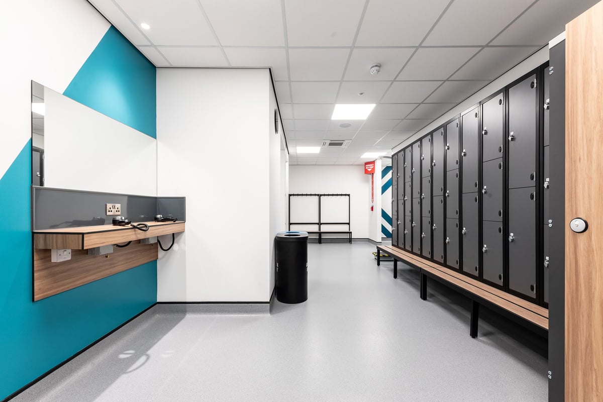 PureGym Crewe Grand Junction Retail Park: Lockers, benches, and a front counter in what appears to be a changing room area.