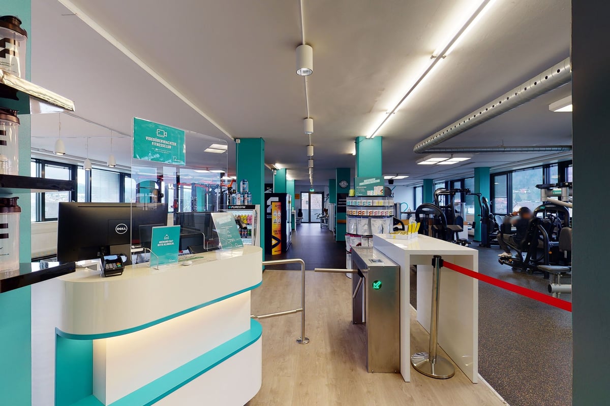 PureGym Dietikon: Reception area with information signage and entry turnstile.