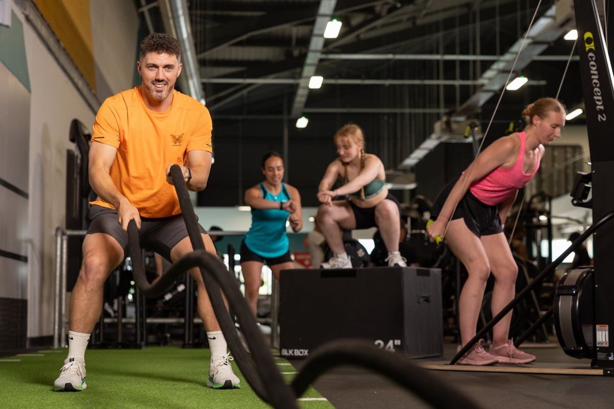 Group of people doing functional exercises with battle ropes in a gym studio