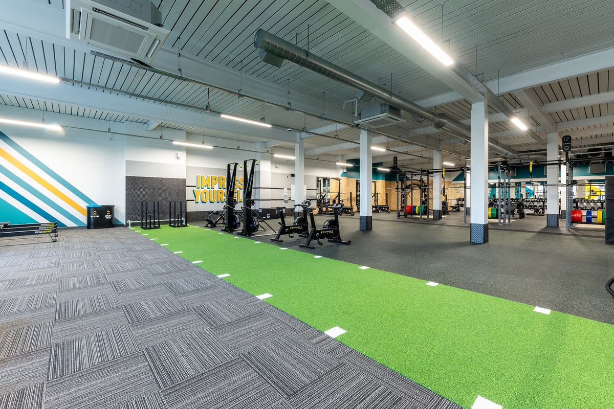 PureGym Glasgow Milngavie: Resistance training area with squat racks, weight plates and artificial turf.