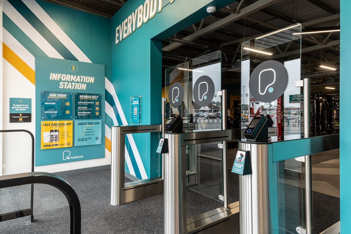 PureGym Barnsley: Checkout area with information desk, turnstiles, and promotional banners.