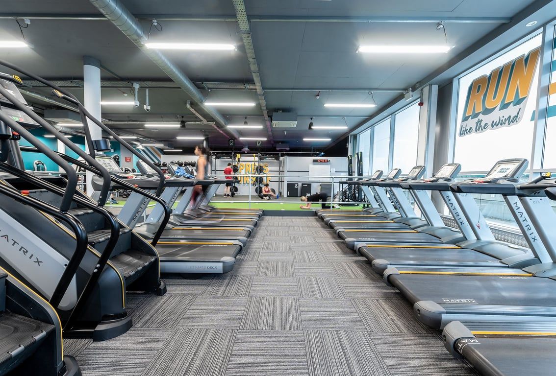 PureGym Walton-on-thames: Rows of treadmills, ellipticals, and recumbent bikes in a brightly lit gym interior.