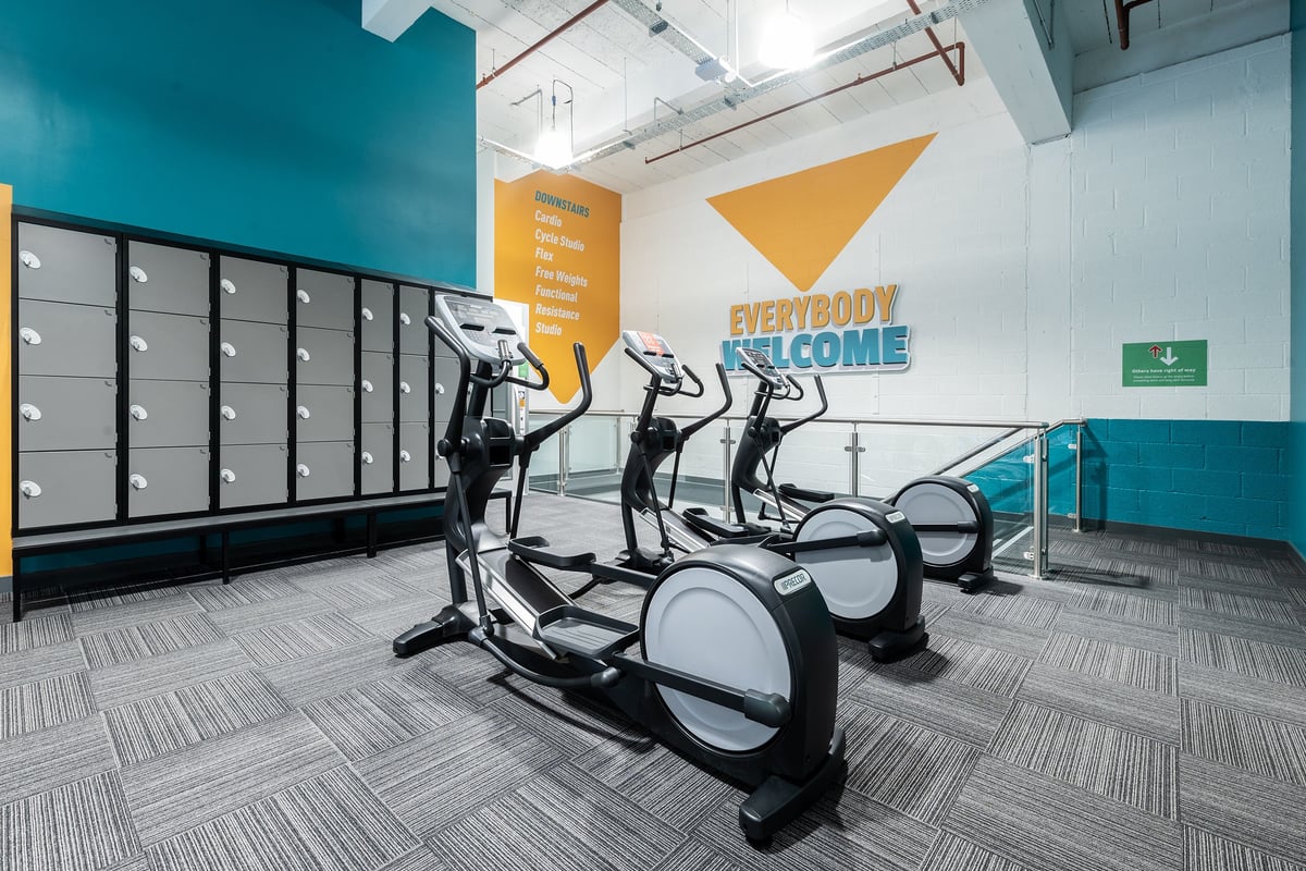 PureGym Gravesend: Rows of elliptical trainers, treadmills in a brightly-lit gym with lockers.