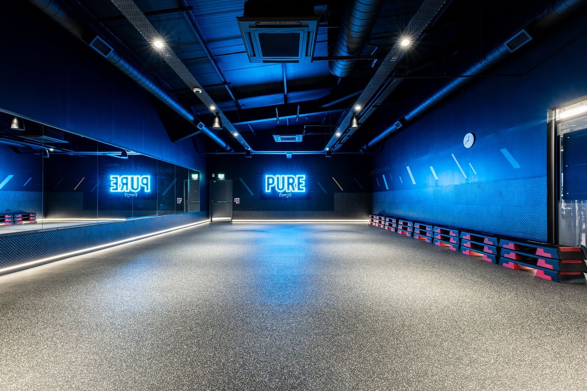 PureGym Glasgow Milngavie: Blue-lit gym with floor markings, equipment storage lockers, and PUBB signage.
