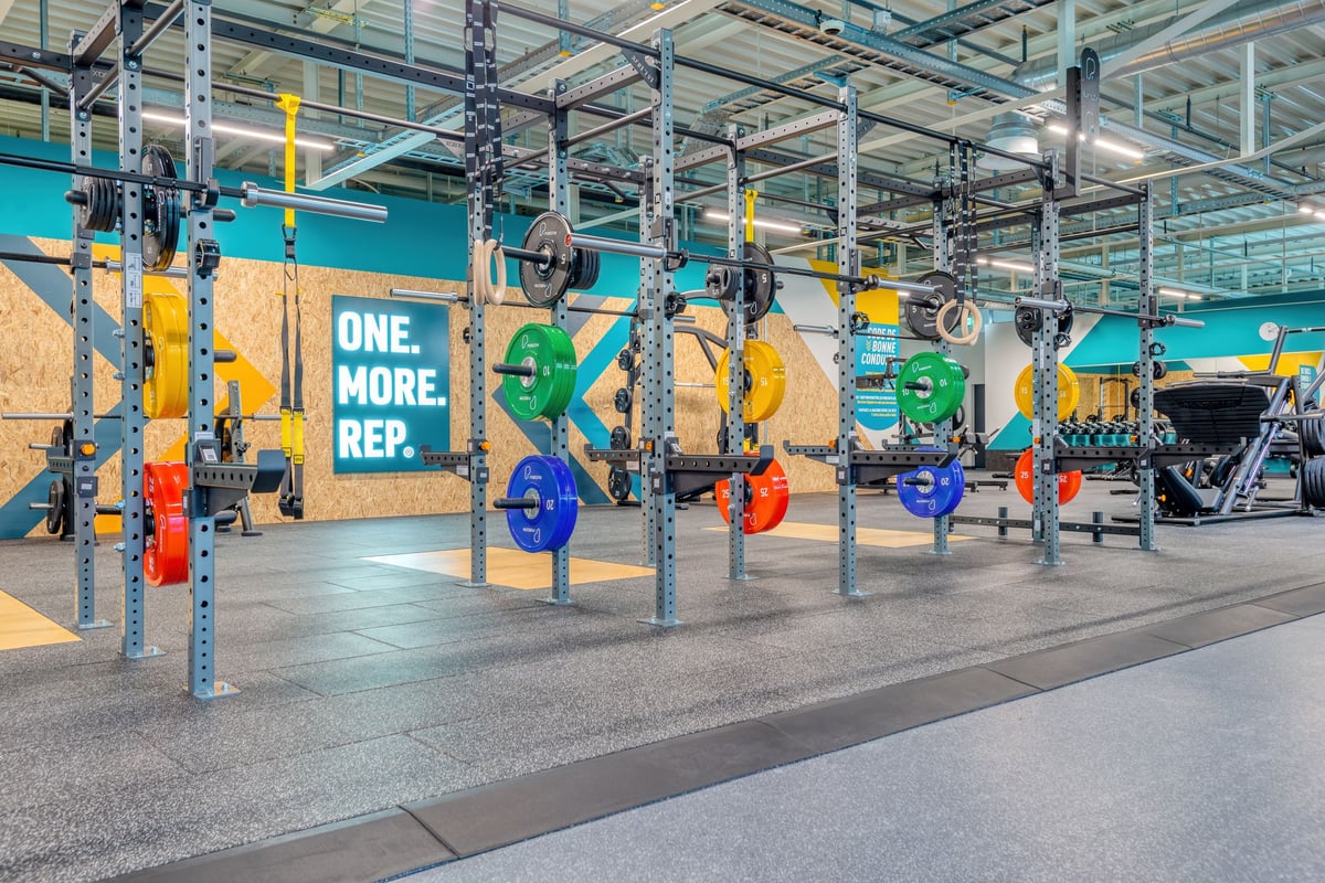 PureGym Martigny: Hantelständer, hängende Boxsäcke und motivierende Beschilderung an den Wänden.