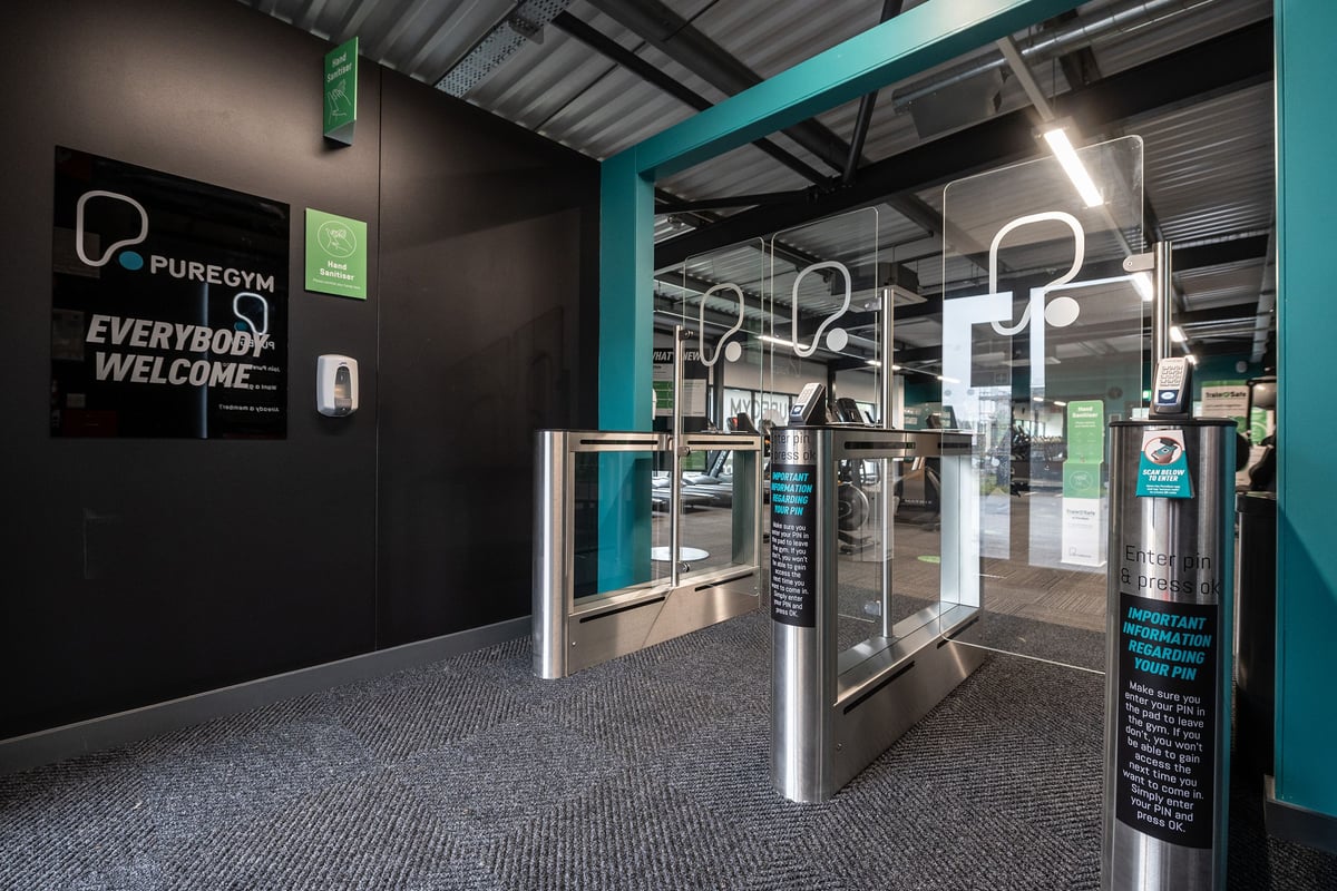 PureGym Kirkcaldy: Entrance turnstiles, black and teal decor, with 'Everybody Welcome' signage.
