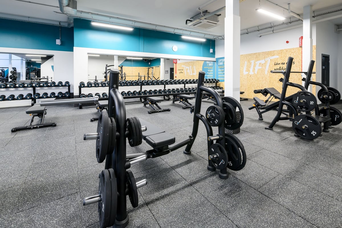PureGym South Ruislip: Rows of weight benches, barbells, weight plates, and rubberized flooring in a gym setting.