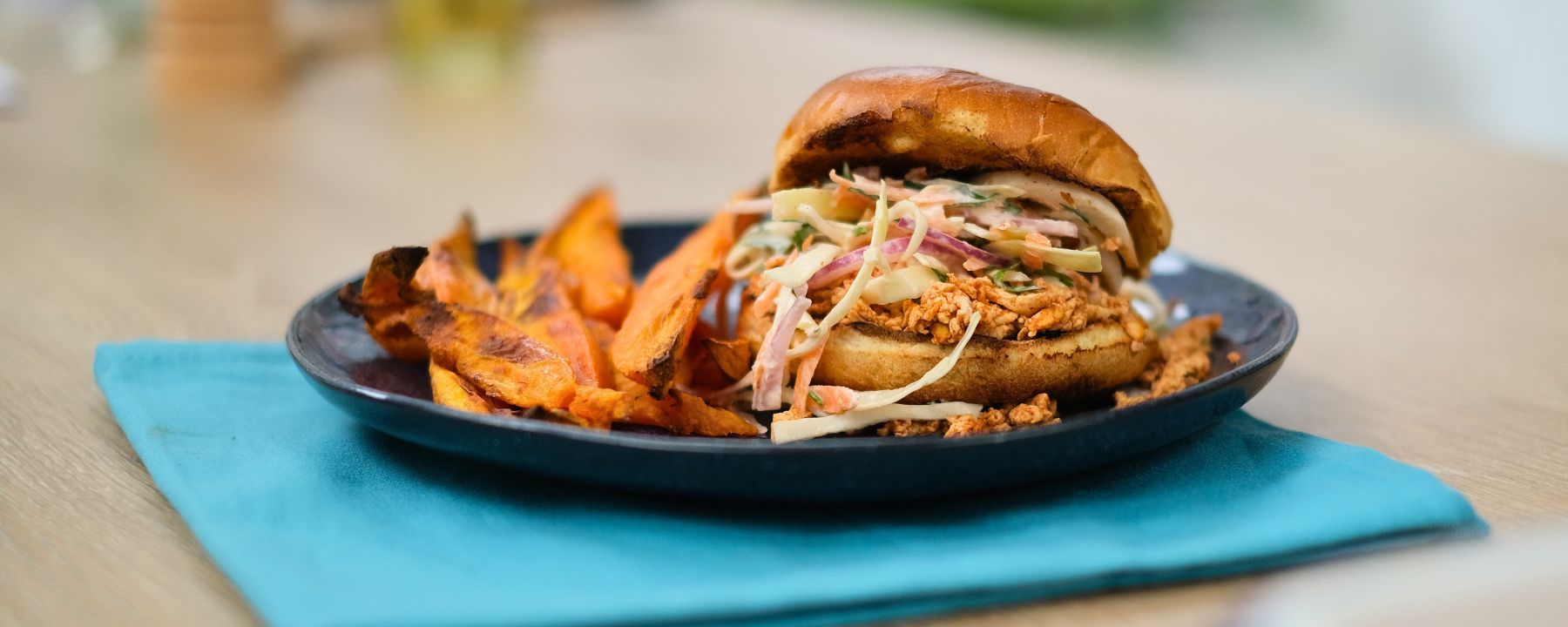 A shredded tofu burger with homemade slaw and sweet potato wedges