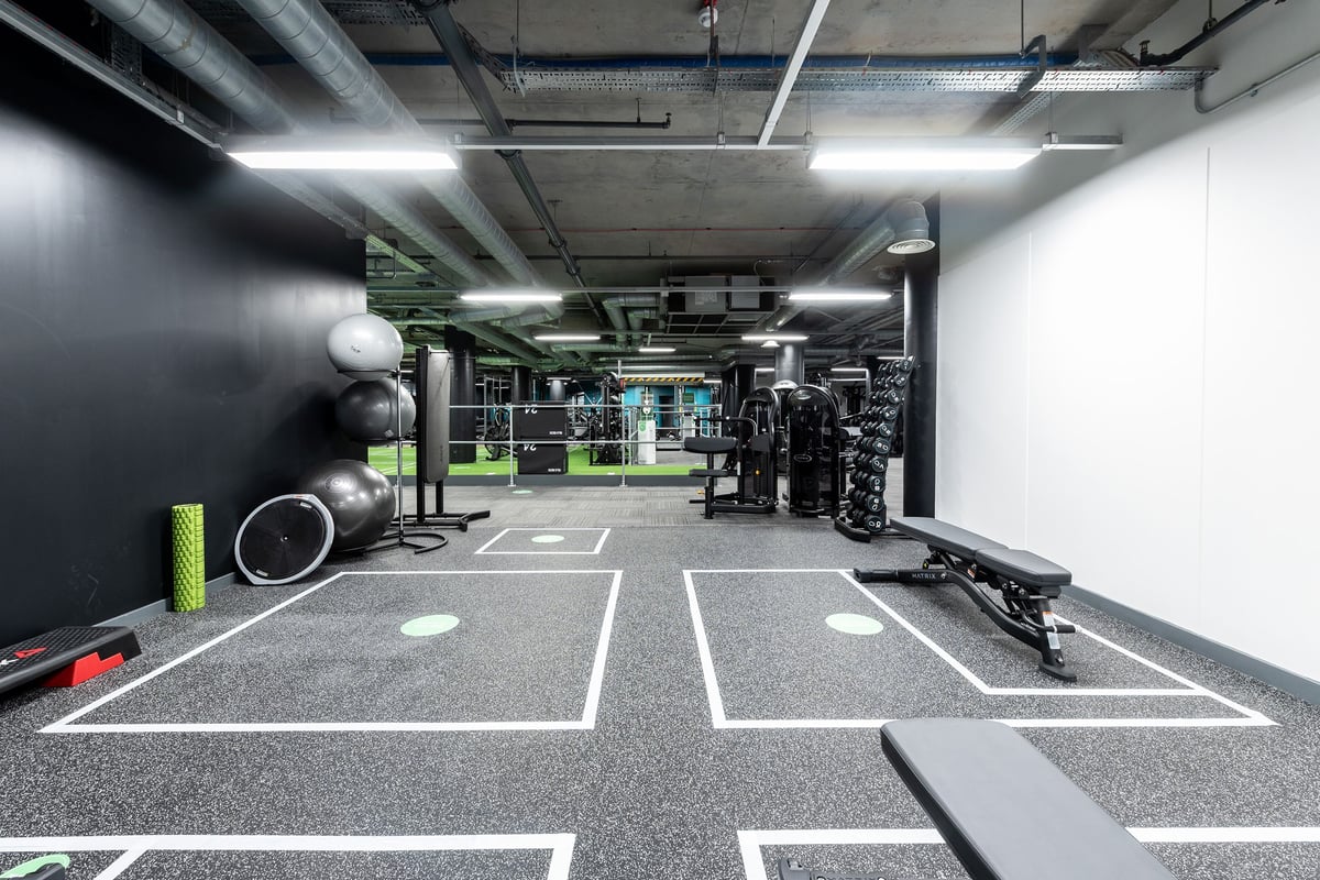 PureGym London Camberwell New Road: Weightlifting area with racks, weights, turf flooring and wall graphics.