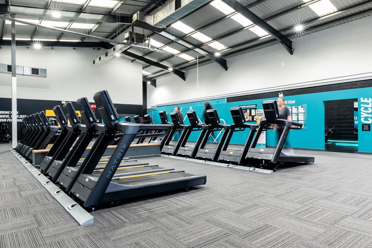 PureGym Leeds Hunslet: Rows of treadmills and exercise bikes lined up in a spacious gym interior.