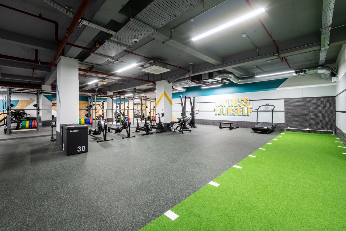 PureGym London Kingston: Weightlifting area with racks, platforms, turf section, and equipment along the walls.