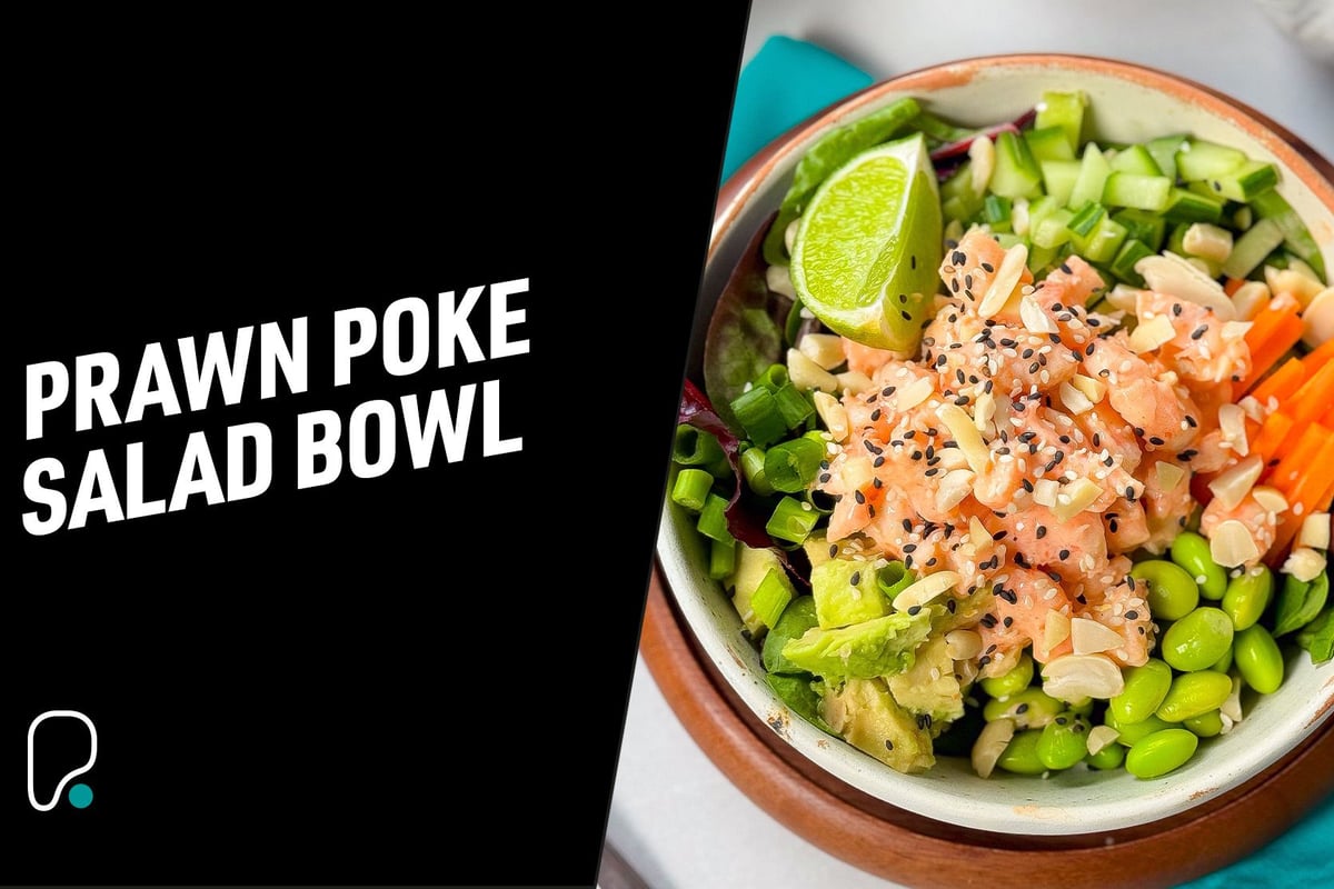 Prawn poke salad bowl with lime wedge, avocado, edamame, carrot, cucumber, and sesame seed