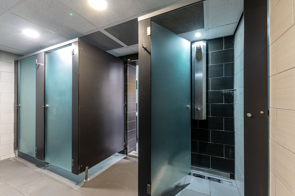PureGym London Muswell Hill: Shower cubicles, frosted glass doors, tiled walls in dark colours.
