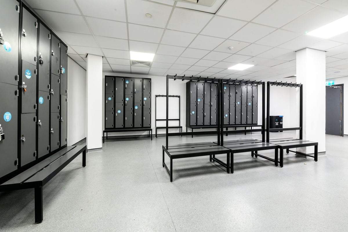 PureGym London Greenwich: Lockers, benches in rows, typical of changing rooms or shower facilities.