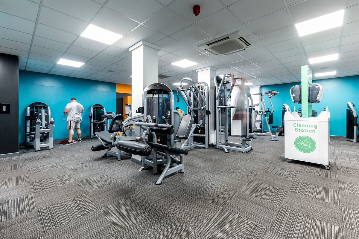 PureGym Luton And Dunstable: Circuit machines, weight racks, benches, and exercise balls in a gym studio with teal walls.