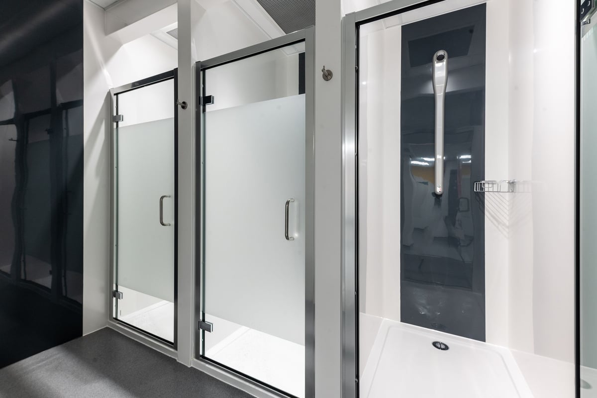 PureGym Hatfield: Glass shower stalls, benches, and lockers for changing.
