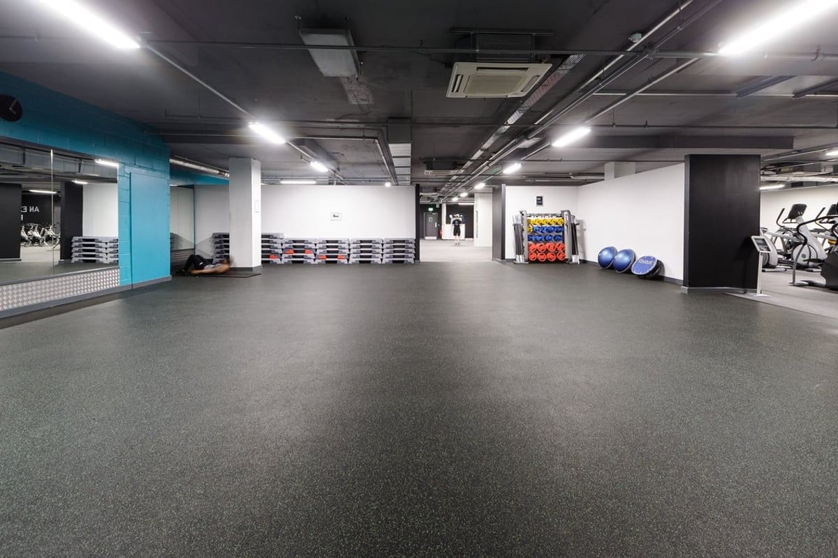 PureGym Derby City Centre: Gym studio with free weights, exercise balls, mirrored walls, and rubberized flooring.