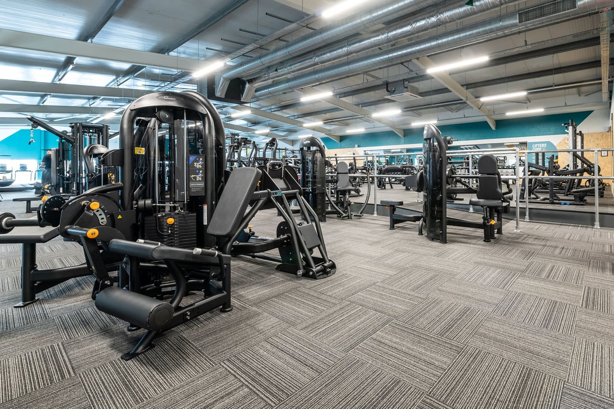 PureGym London Colney: Weight machines, resistance equipment, freeweights, patterned rubberized flooring in a gym setting.