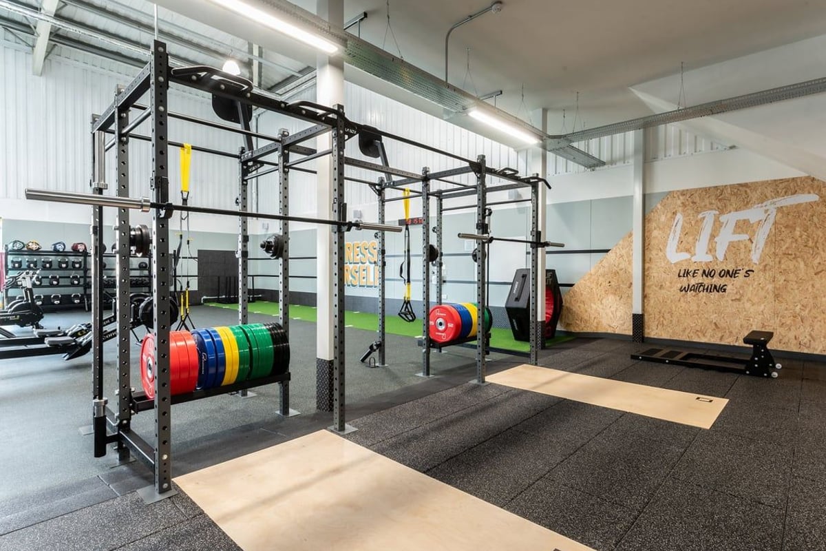 PureGym Grantham Discovery Retail Park: Squat racks, weight plates, turf area, rubberized floor, motivational mural on wall.