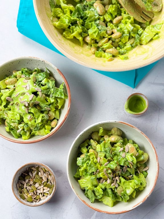 Green salad with beans and seeds in bowls on a light surface with a blue cloth