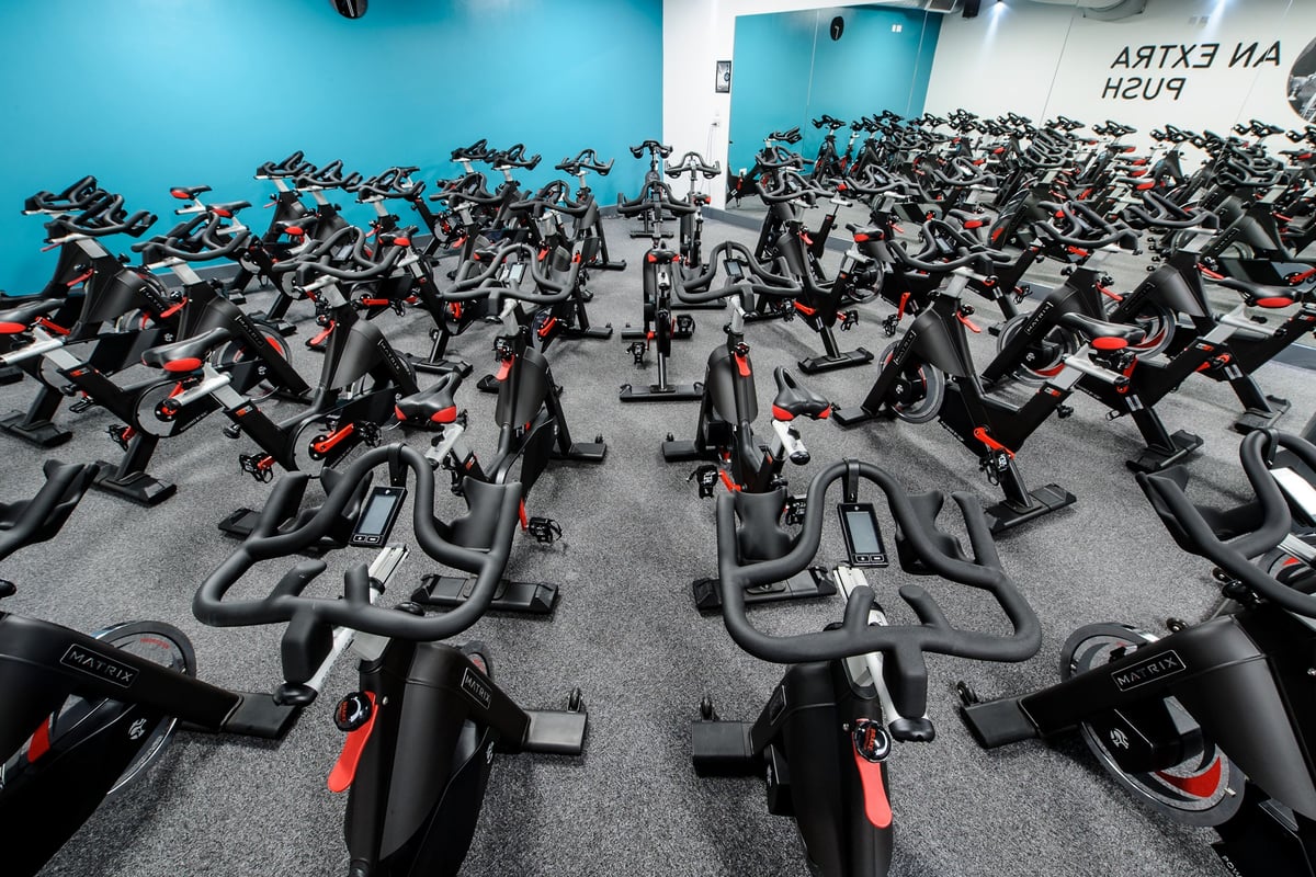 PureGym London Wembley: Rows of stationary exercise bikes fill a blue-tinted gym studio.