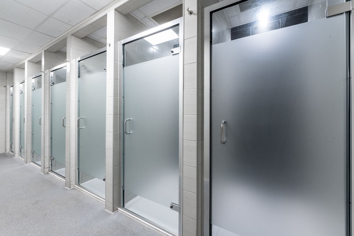 PureGym Loughborough: Rows of private shower stalls with frosted glass doors and handles.