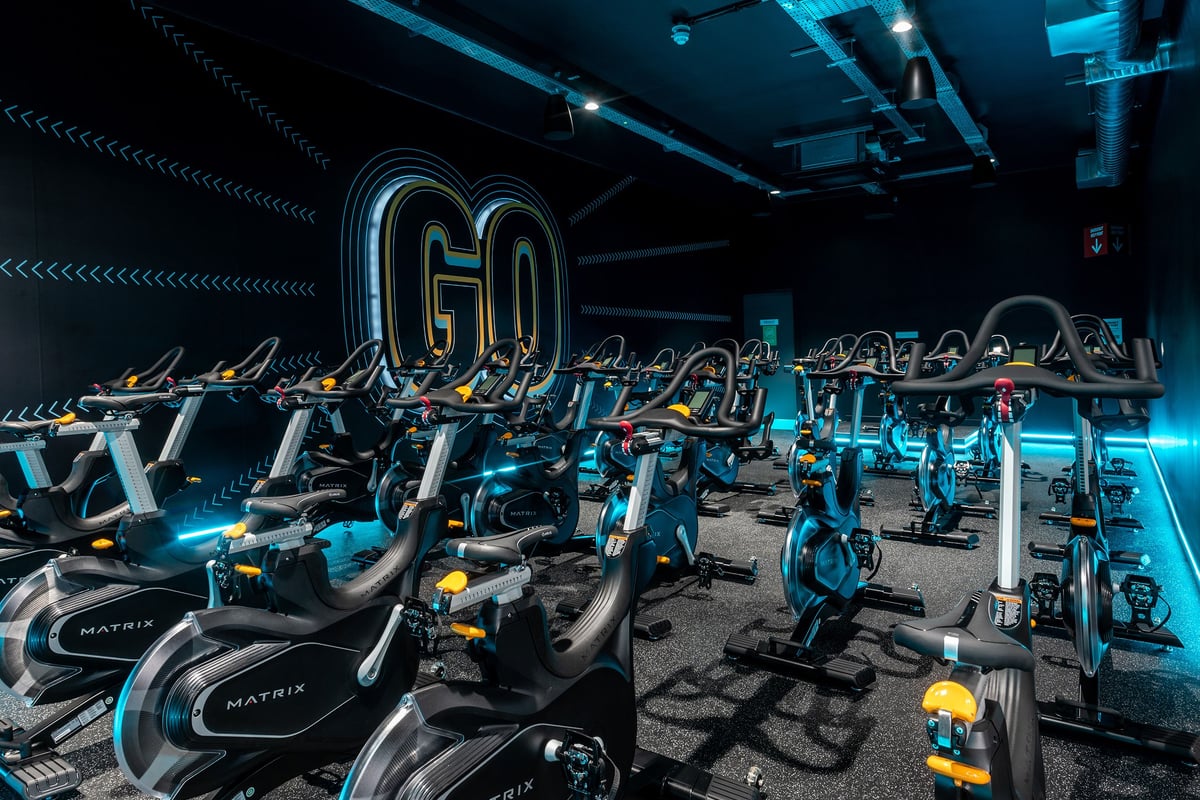 PureGym Milton Keynes Kingston Centre: Rows of stationary bikes, treadmills, and weight stations in a dimly lit gym interior.