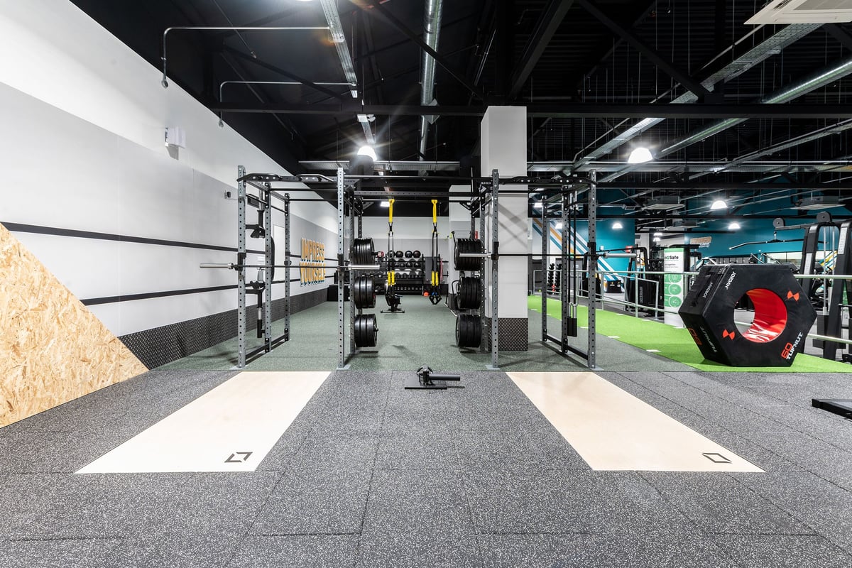 PureGym Bracknell: Rubberized flooring, weight racks, mirrors, exercise equipment in industrial-style gym.