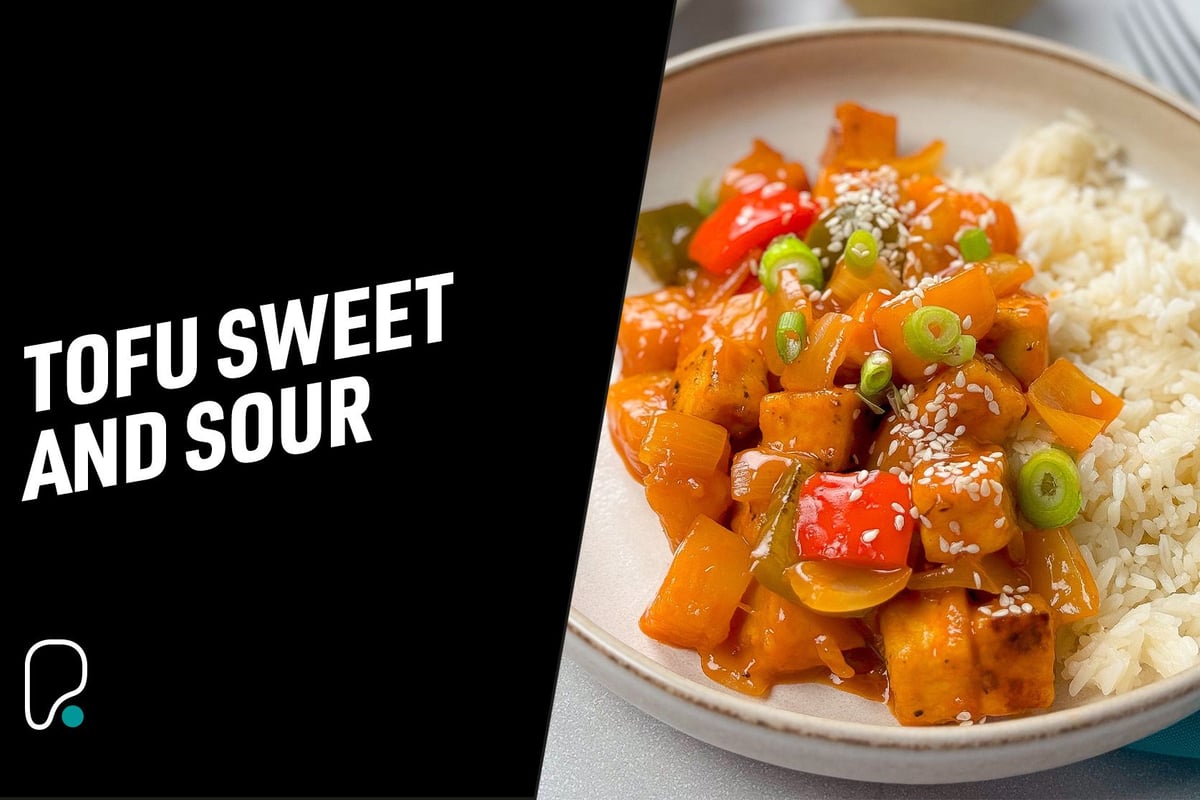 Tofu sweet and sour with vegetables and white rice on a plate garnished with sesame seeds