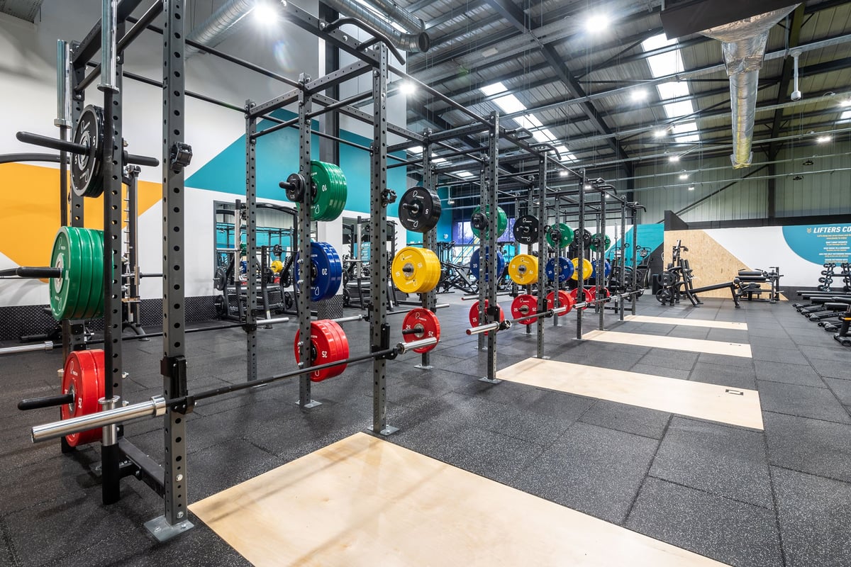 PureGym Dunfermline: Racks with weighted plates of various colours, rubberised floors, and squat platforms.