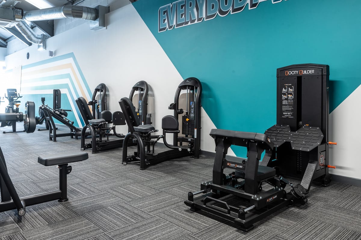 PureGym Derby Meteor Centre: Weight machines, benches, mirrored wall, teal accent wall with 'Everybody' signage.
