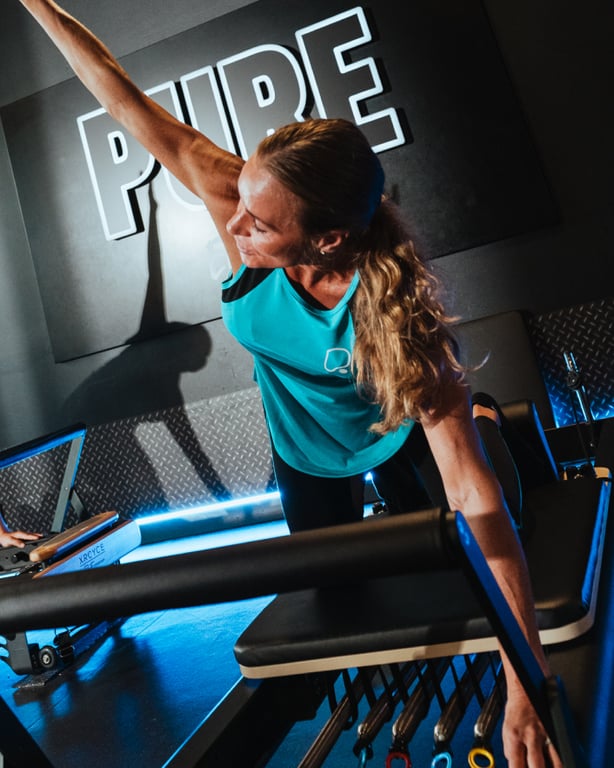 Persona che utilizza un macchinario per il Reformer Pilates in una moderna struttura PureGym