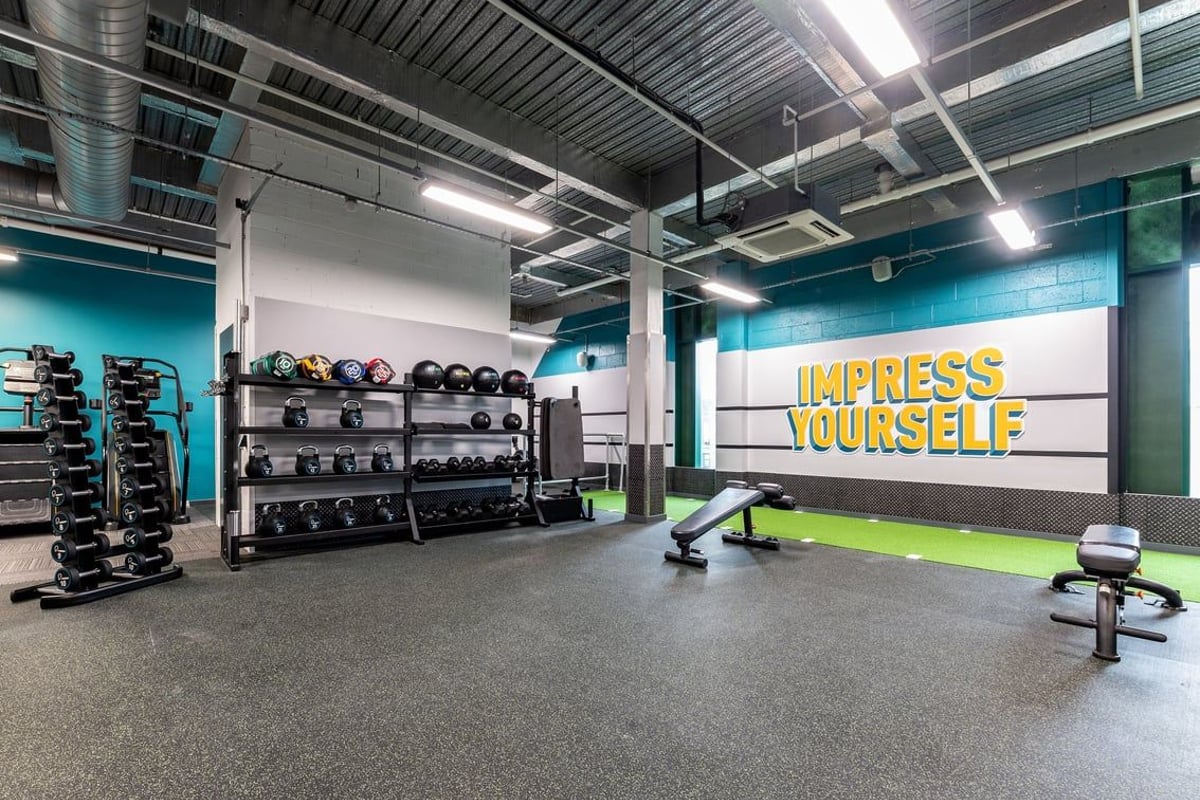 PureGym Newcastle Eldon Garden: Weights racks, benches, rubberized floors, wall motivational slogan "Impress yourself"