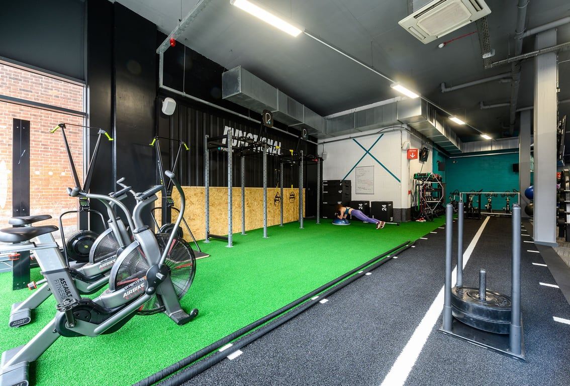 PureGym London Acton: Turf area, spinning bikes, plate-loaded machines, lockers, rubberized floor.