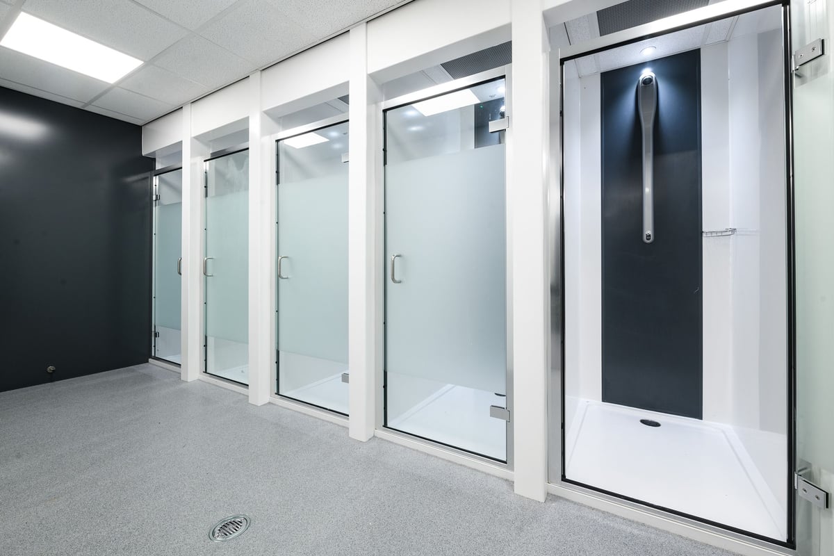 PureGym Leeds Thorpe Park: Rows of frosted glass doors and shower stalls, typical of a changing room facility.