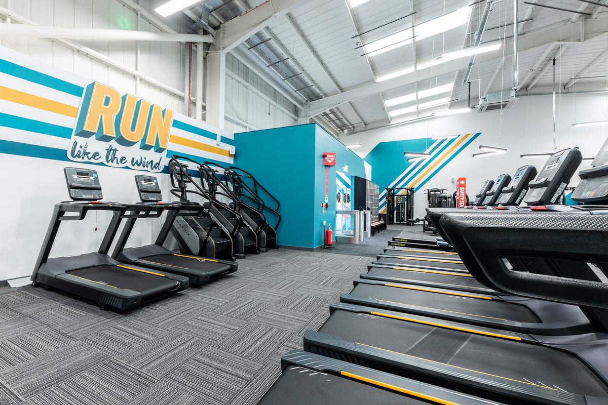 PureGym Eastbourne: Rows of treadmills, large motivational wall signage, and rubber flooring - a typical cardio area.