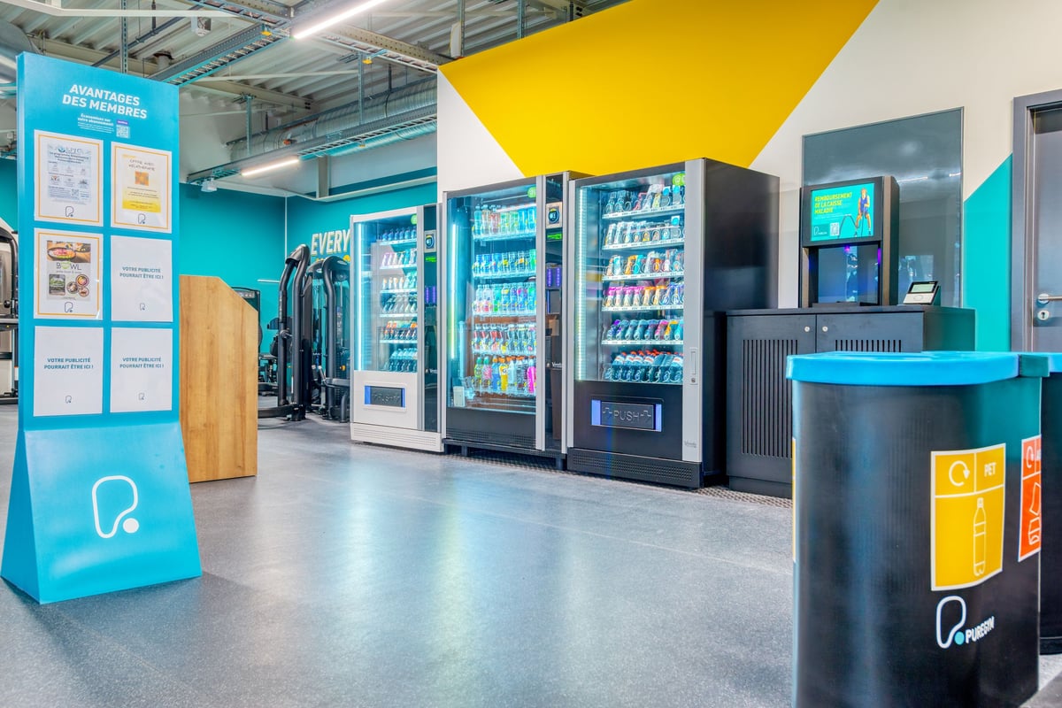PureGym Martigny: Verkaufsautomaten, Sitzbereiche und farbenfrohe Wände.