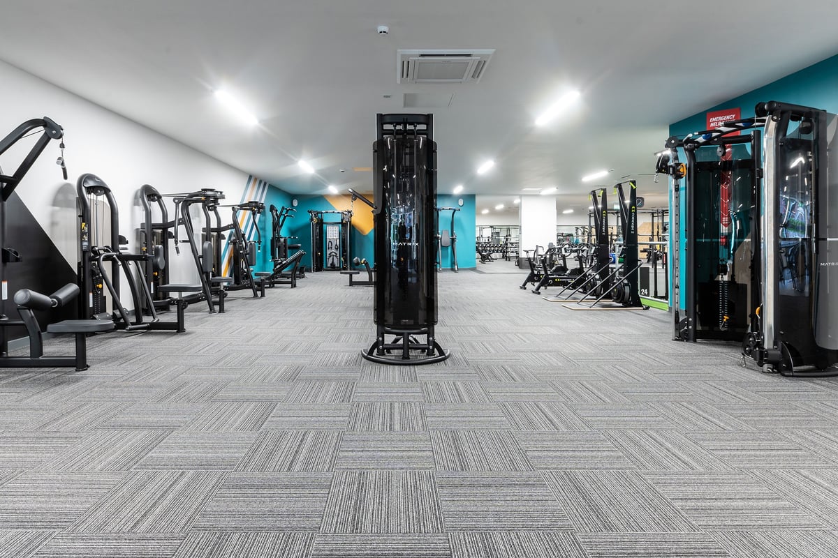 PureGym Tyldesley: Weight machines, cable crossovers, resistance bands, benches, rubberized floors in a modern gym interior.